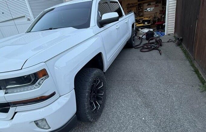 Side of a white Chevrolet Silverado with dressed tires