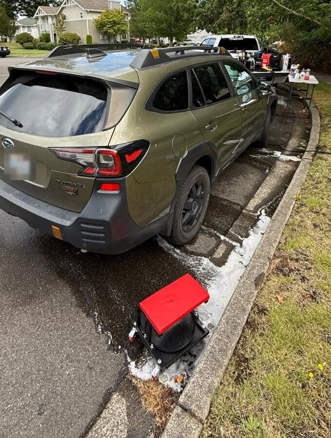 Green Subaru Outback being washed at the curb